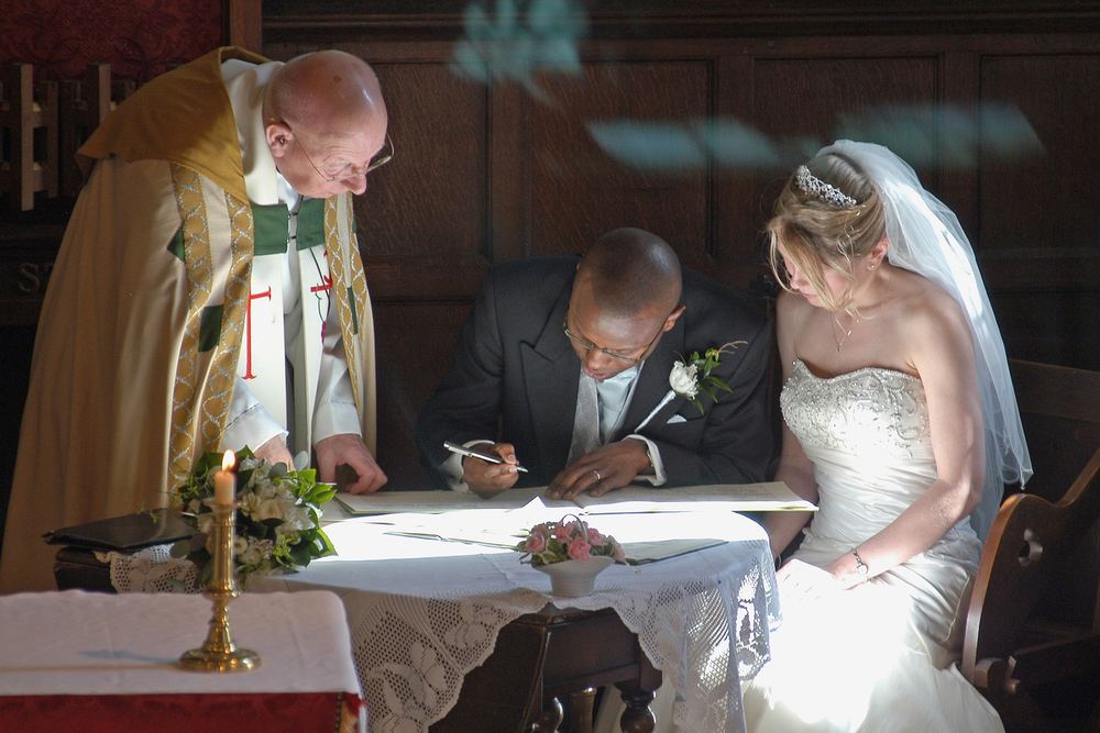The vicar and Alison watch new husband Michael sign the register at St John the Baptist Church, Stamford Bridge, York.