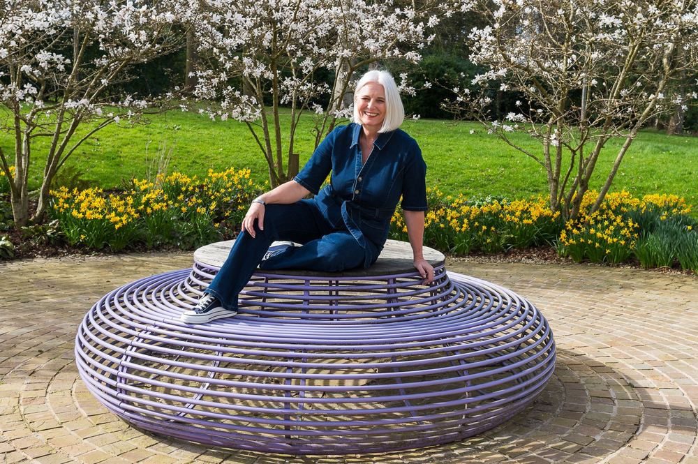 A mature model posing on a wire bench at Rudding Park for Midlife Magic.
