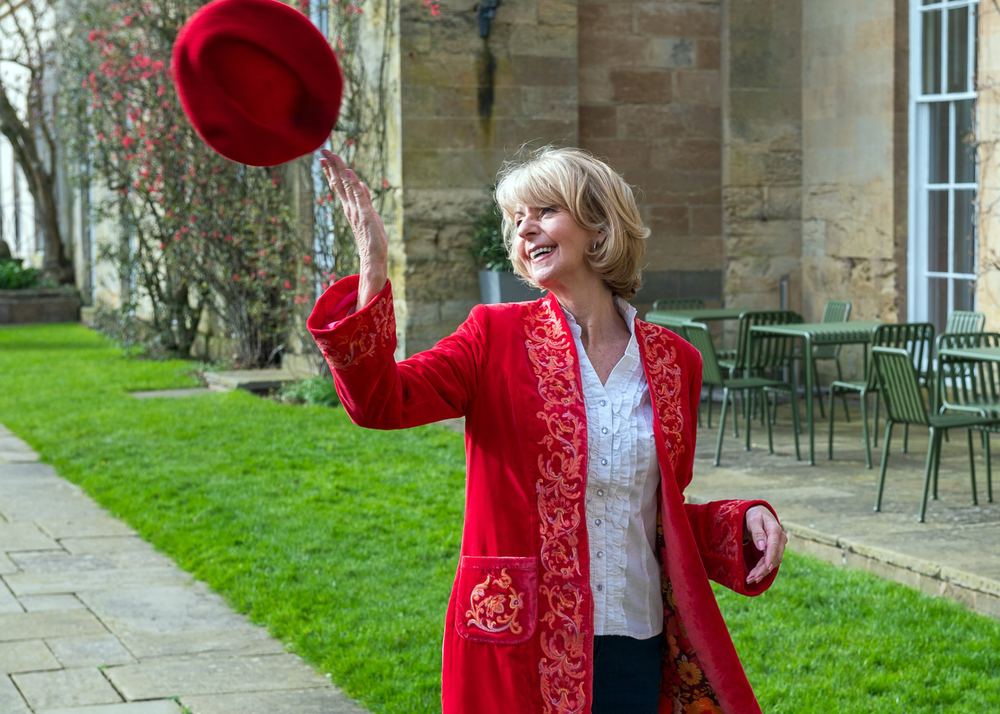 A model in a bright red jacket tosses her beret in the air.
