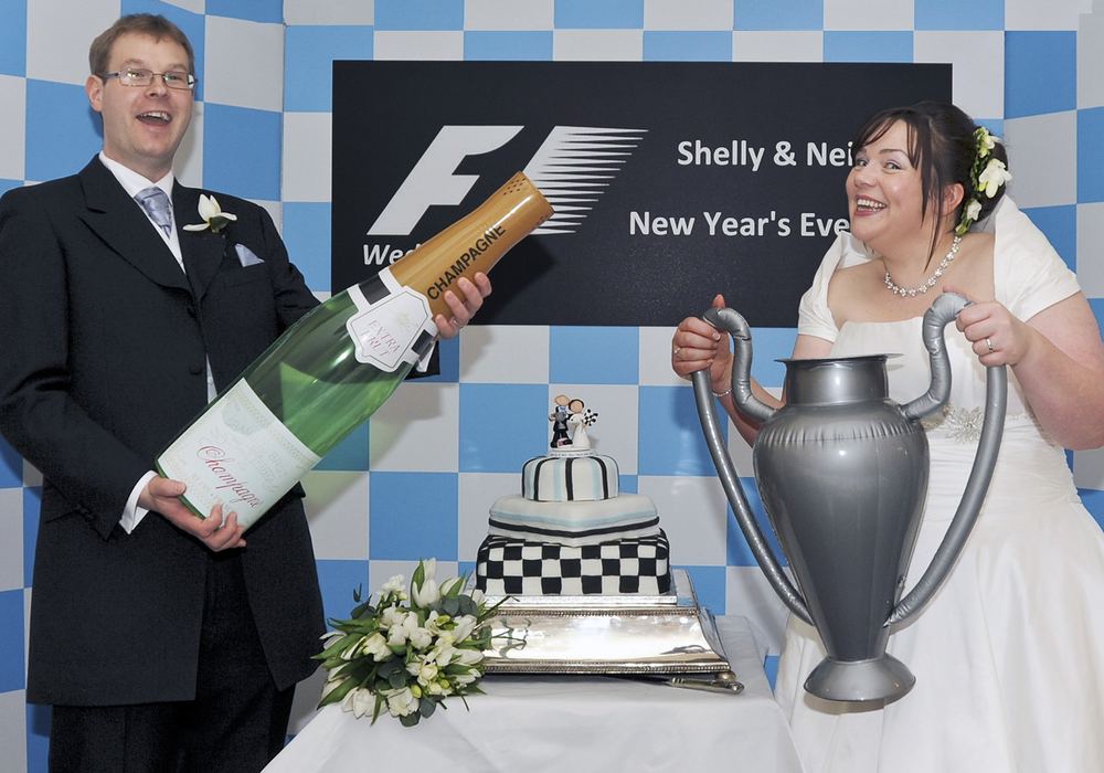 F1 fans Shelley & Neil with F1-inspired props and their wedding cake.