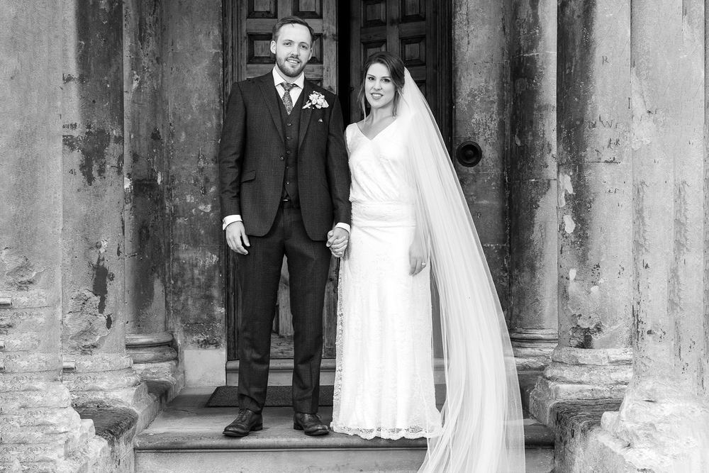 A traditional black & white portrait of a bride and groom on stone steps.