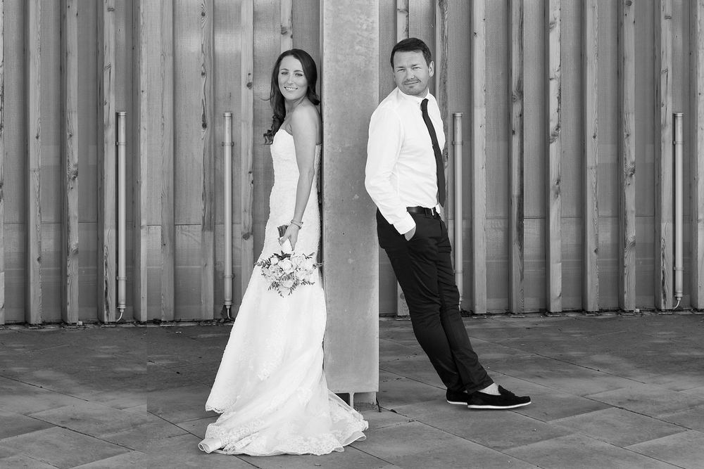 A black & white portrait of newly-weds, back to back.