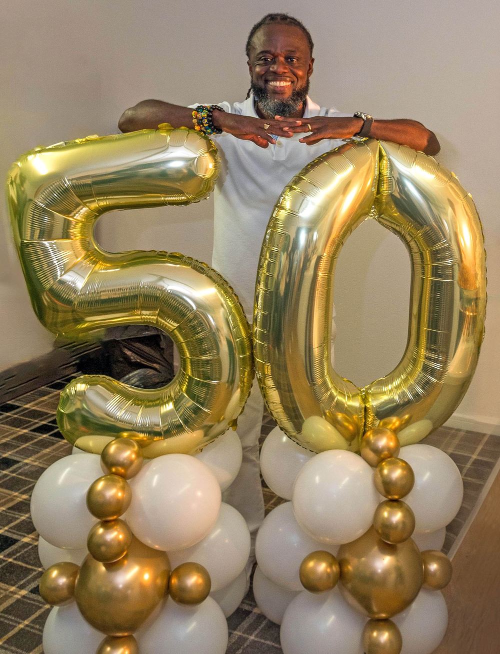 The birthday boy poses behind a wall of 50 balloons.