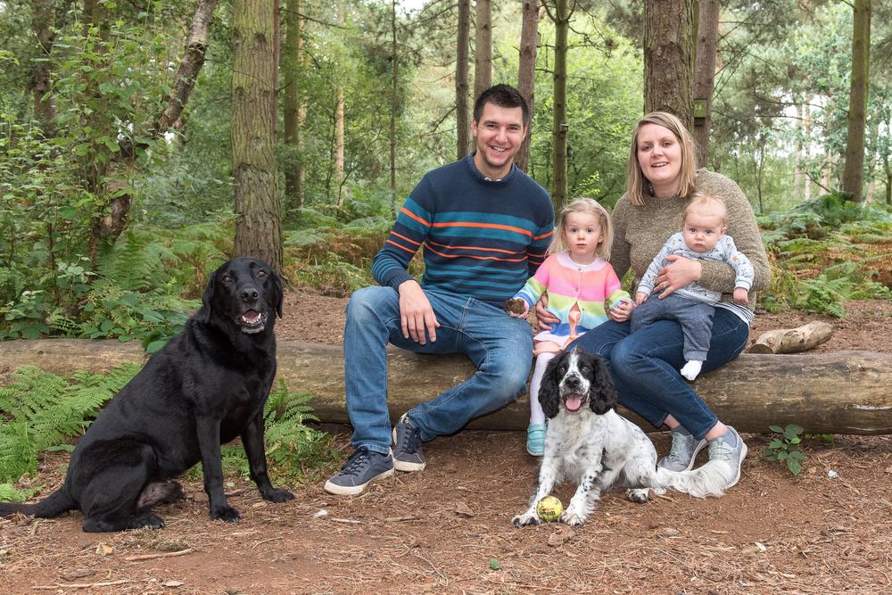 A family portrait in the woodland, with two young children and the family dogs.