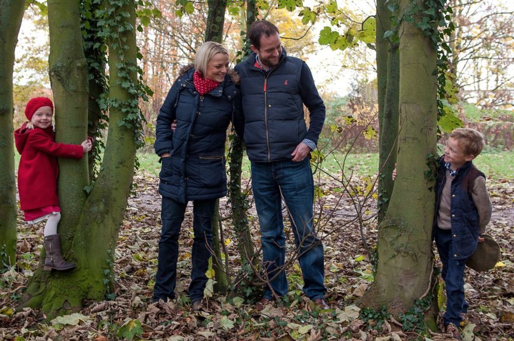Parents with their two small children in an autumnal woodland.