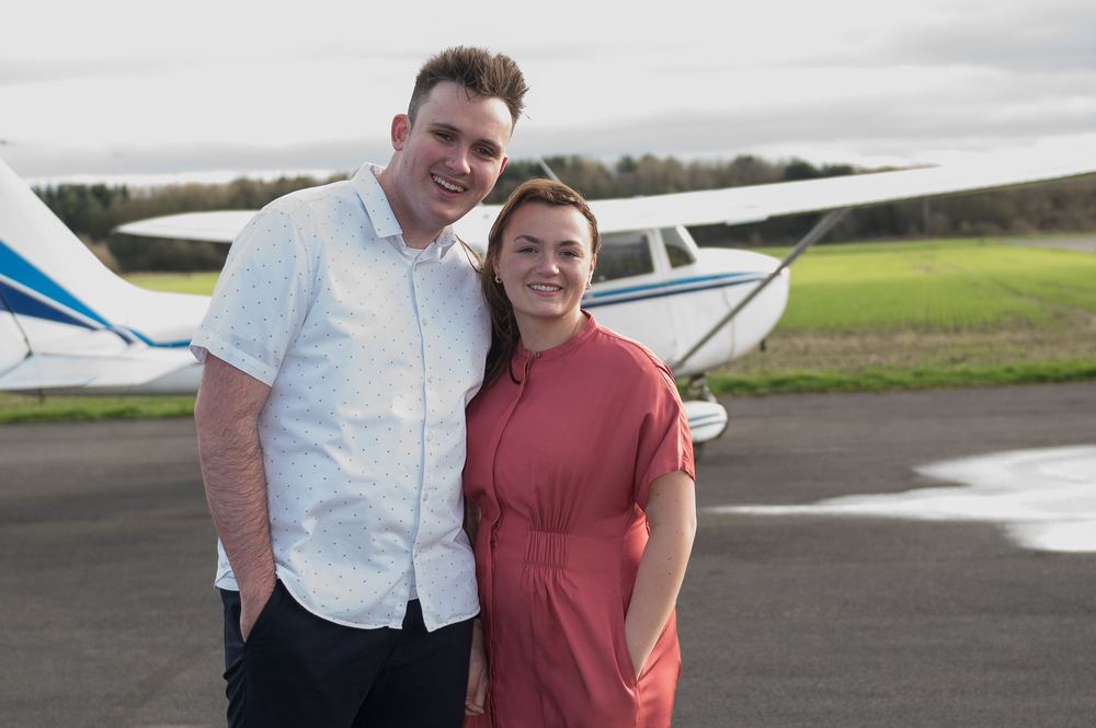 A newly engaged couple in front of their plane.