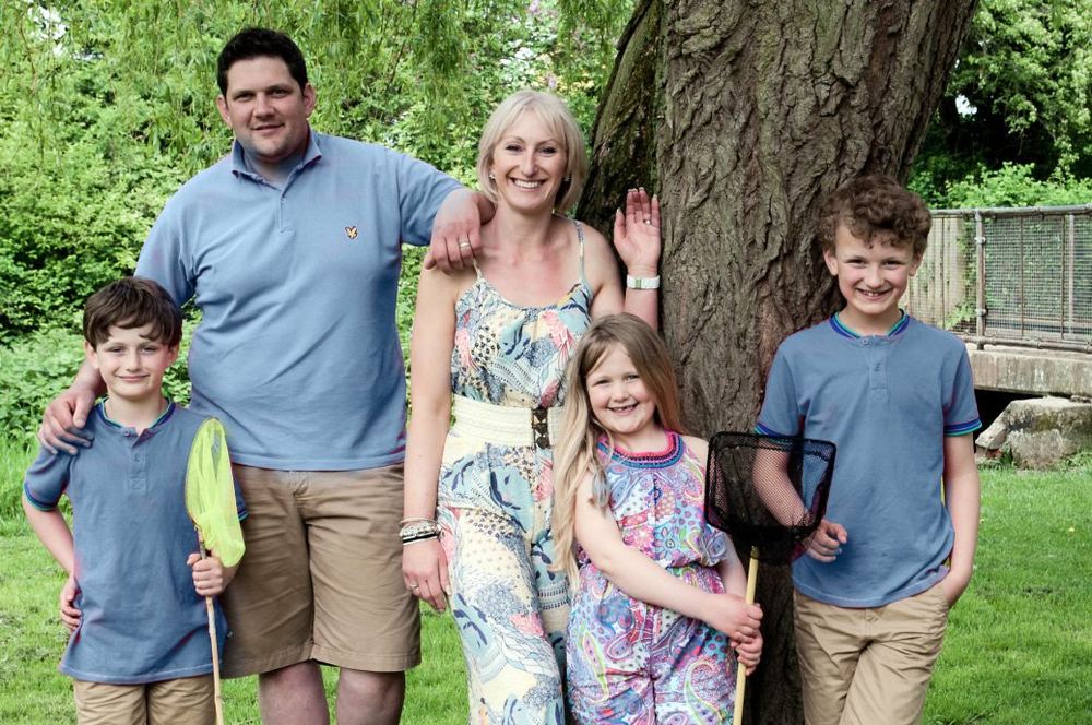 Parents and their three children, posed by a tree.
