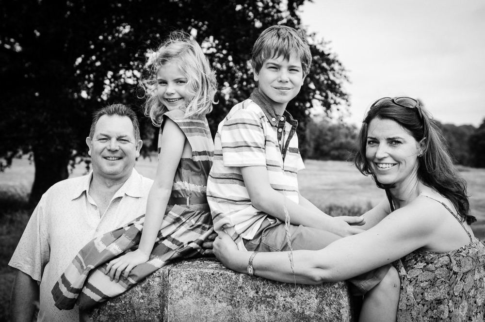 Parents with their son and daughter, seated on a stone plinth.